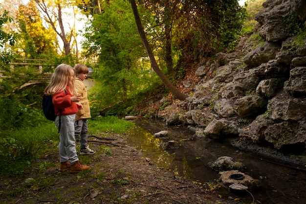 Niños de tiro completo explorando la naturaleza juntos