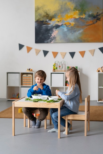 Foto niños de tiro completo sentados juntos en la mesa