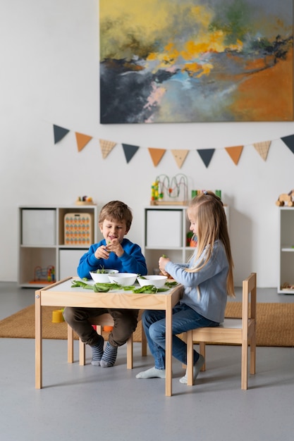 Niños de tiro completo sentados juntos en la mesa