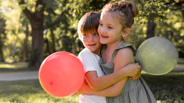 Niños de tiro medio abrazándose al aire libre