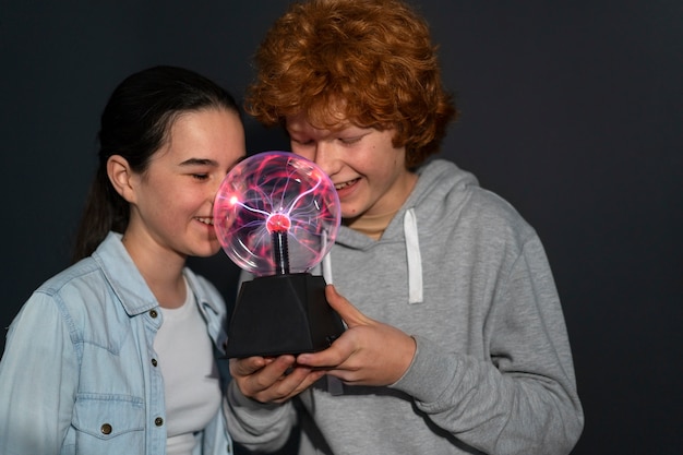 Foto niños de tiro medio interactuando con una bola de plasma