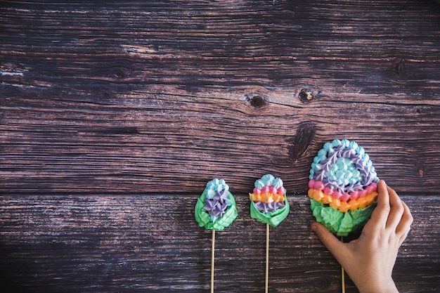 Los niños toman a mano un colorido dulce merengues caseros en forma de huevos sobre fondo de madera Muchos céfiros dulces Imagen de postre de vista superior de moda