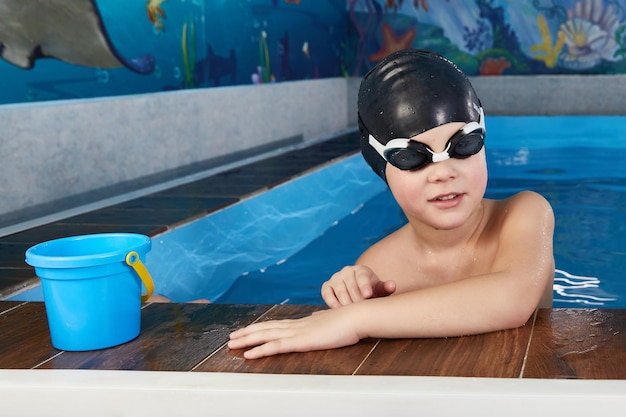 Niños tomando un descanso durante la clase de natación en la piscina cubierta