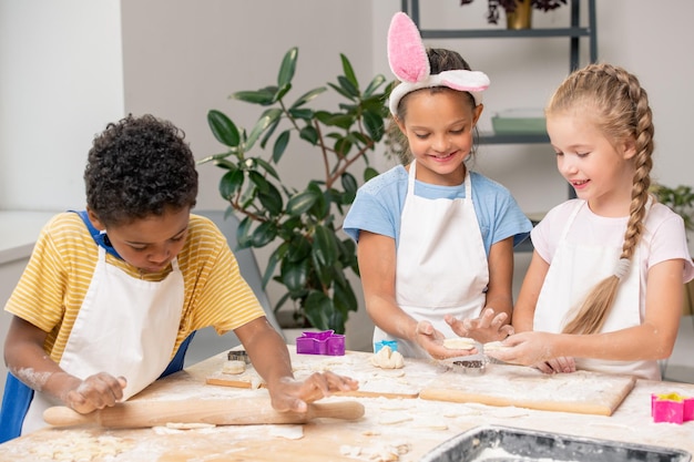 Niños trabajando con harina y huevos mientras su hijo los bate