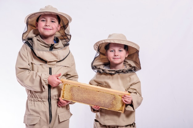 Niños en trajes de apicultor posando en blanco.