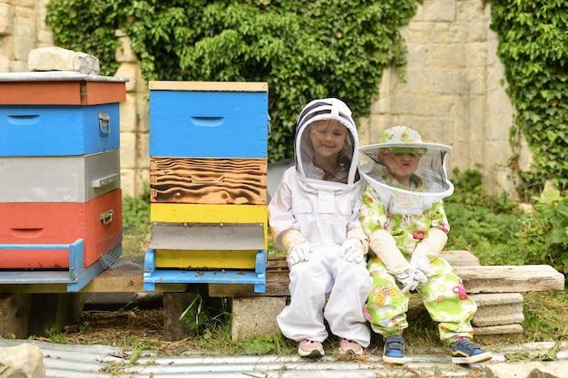 Niños con trajes protectores cerca de la colmena.