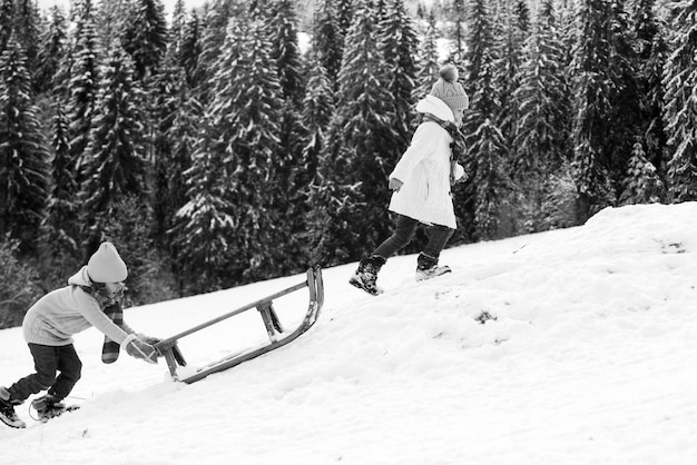 Niños en trineo niños niño y niña juega afuera en la nieve paisaje navideño