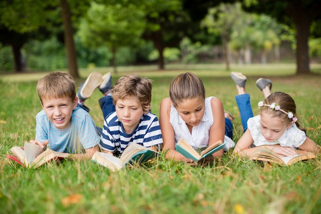 Niños tumbados en la hierba y leyendo libros