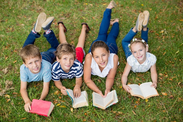 Niños tumbados en la hierba y leyendo libros