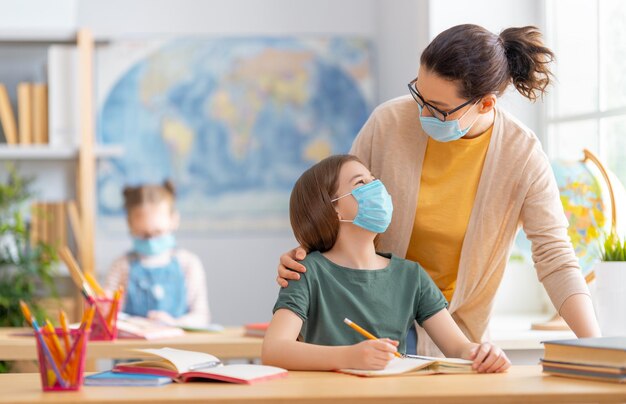 Los niños usan mascarillas aprendiendo en clase