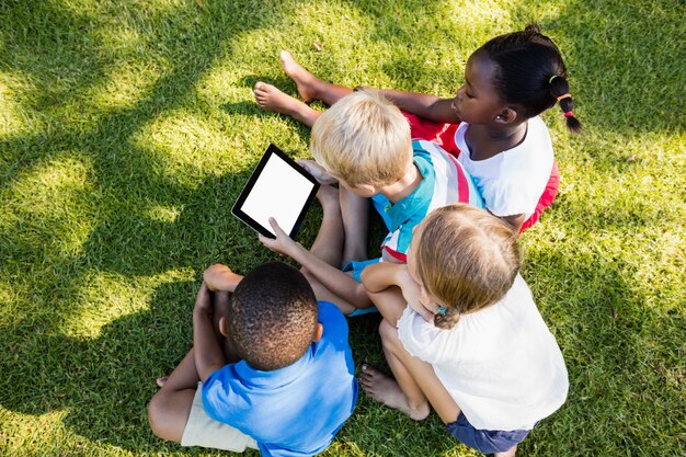 Niños usando tableta digital durante un día soleado