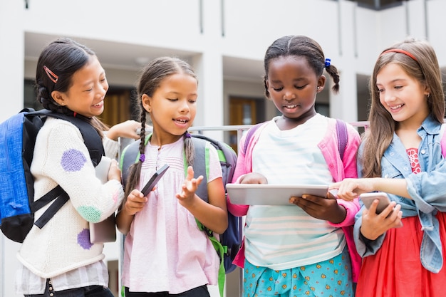 Niños usando tableta digital y teléfono móvil en la terraza de la escuela