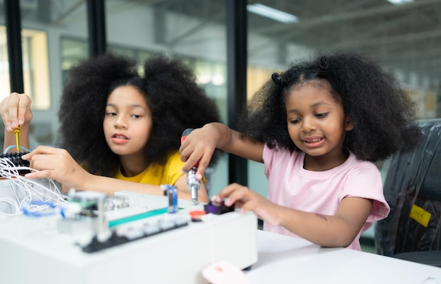 Niños usando la tecnología del robot de mano y divirtiéndose Aprendiendo la placa de circuitos electrónicos