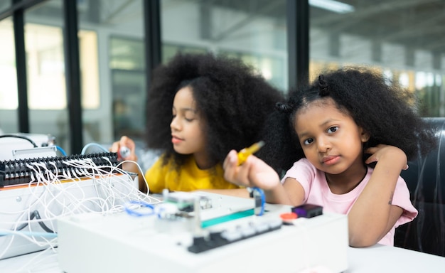 Niños usando la tecnología del robot de mano y divirtiéndose Aprendiendo la placa de circuitos electrónicos