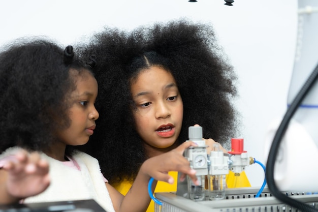Niños usando la tecnología del robot de mano y divirtiéndose Aprendiendo la placa de circuitos electrónicos