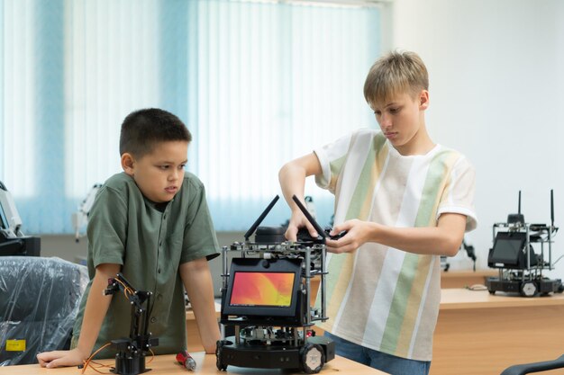 Niños usando la tecnología del robot de mano y divirtiéndose Aprendiendo la placa de circuitos electrónicos