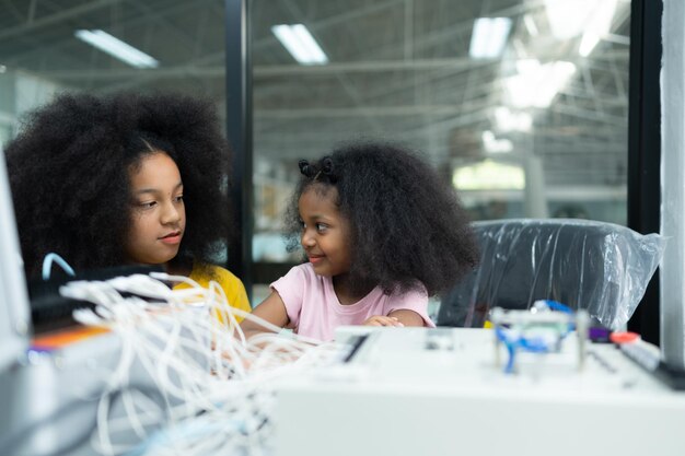 Niños usando la tecnología del robot de mano y divirtiéndose Aprendiendo la placa de circuitos electrónicos
