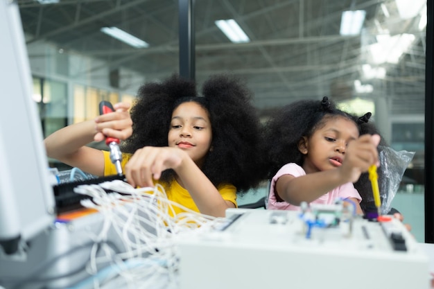 Niños usando la tecnología del robot de mano y divirtiéndose Aprendiendo la placa de circuitos electrónicos