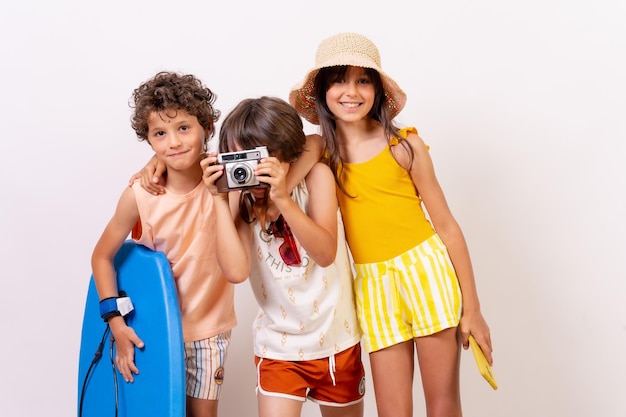 Foto niños vacaciones de verano en un niño de fondo blanco tomando una foto con una cámara vintage mirando a la cámara