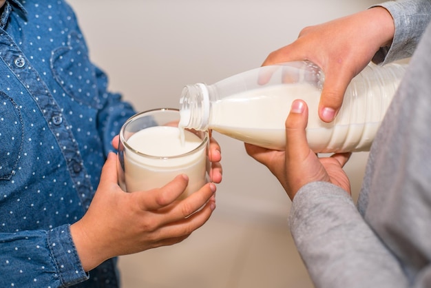 niños vertiendo leche en un primer plano de vaso.