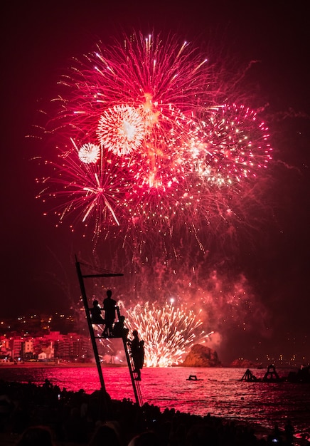 Foto niños viendo fuegos artificiales en el mar.