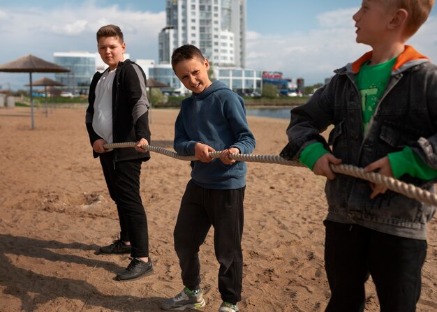 Foto niños de vista frontal jugando tira y afloja en la playa