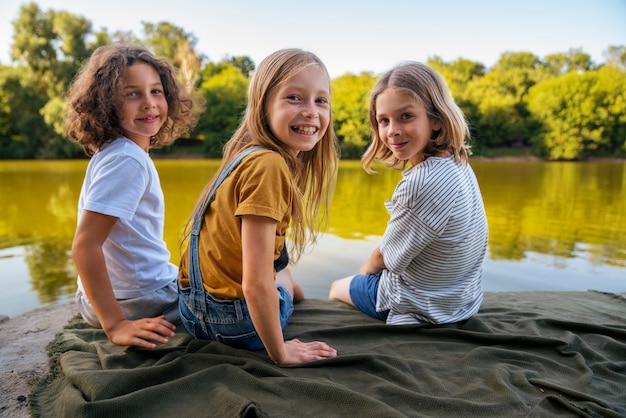 Foto niños de vista lateral sentados en una manta al aire libre