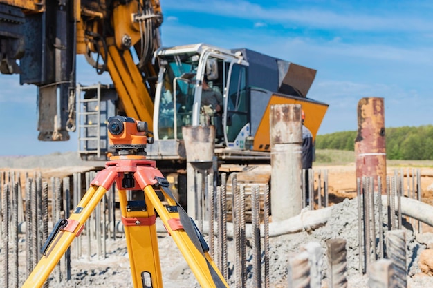 Nivel geodésico en el fondo de una plataforma de perforación Máquina de perforación hidráulica en el sitio de construcción Campo de pilotes Plataforma de perforación de trabajo cuando se conducen pilotes perforados