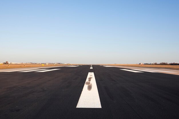 Foto nivel de superficie de la pista larga del aeropuerto con marcaje direccional en un cielo despejado