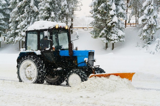 Nivelador de soprador de neve azul limpa estrada de estância de esqui coberta de neve nas montanhas ou rua da cidade Floco de neve de inverno Queda de neve nevoeiro frio neblina clima Espaço de cópia horizontal