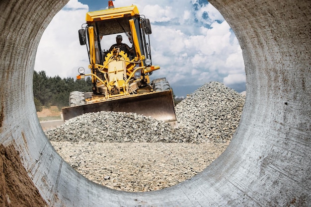 Niveladora de caminos para nivelación de terrenos en un sitio de construcción Potente máquina de construcción para nivelación de terrenos y excavación Primer plano Equipo de construcción profesional Vista desde la tubería grande