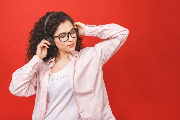 Niza alegre chica estudiante morena de pelo rizado escuchando música, bailando