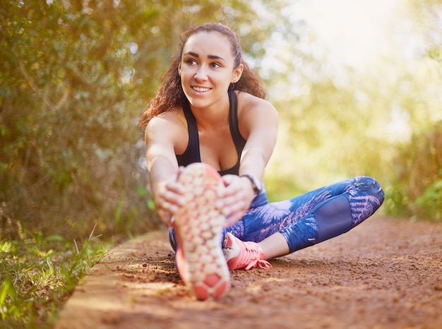 No aumente sus posibilidades de lesionarse al no calentar Foto de una joven deportista que se estira antes de correr