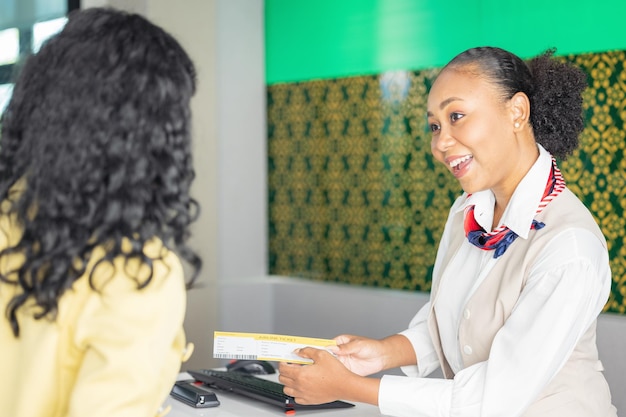 No balcão de check-in do aeroporto, um passageiro entrega seus documentos ao gerente por meio de um bilhete de balcão