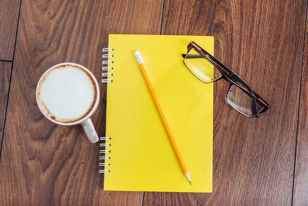 No caderno de madeira lápis, café e flores.