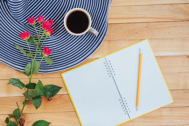 No caderno de madeira lápis, café e flores.