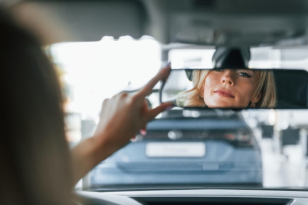 Foto no carro mulher em roupas formais está dentro de casa no salão de automóveis