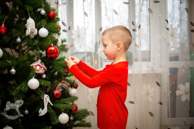 No dia de Ano Novo, um menino decora uma árvore de Natal em casa