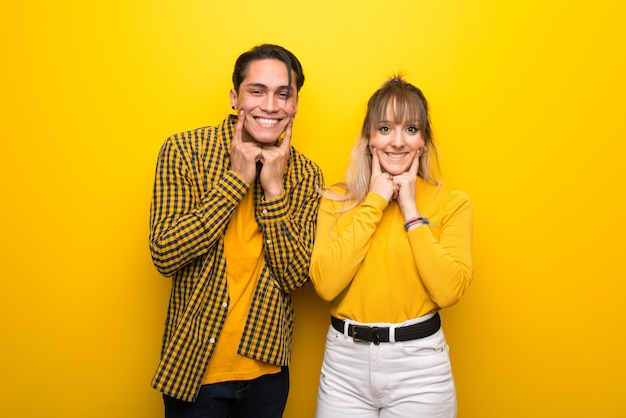 No dia dos namorados Jovem casal sobre fundo amarelo vibrante sorrindo com uma expressão feliz e agradável