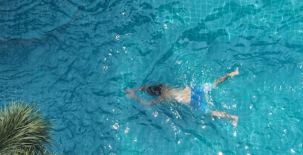 No dia ensolarado de verão, piscina de cor azul, água clara e pessoas curtindo