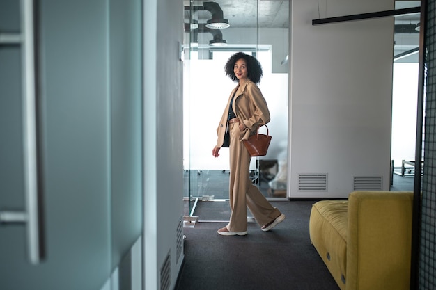No escritório. Empresária confiante e determinada entrando em um escritório moderno com portas de vidro