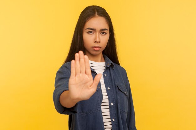 No está prohibido hacer Retrato de niña molesta en camisa de mezclilla que muestra detener el gesto de rechazo prohibición señal de mano advertencia de problemas que disminuyen el conflicto y los problemas en el estudio interior tiro aislado