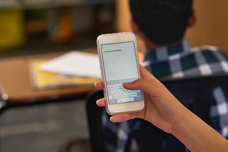 Foto no exactamente cautivado por el plan de la lección foto de una colegiala no identificable usando su teléfono inteligente en clase