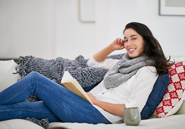 No hay amigos tan leales como un amigo Foto de una mujer joven sentada en la sala de estar leyendo un libro