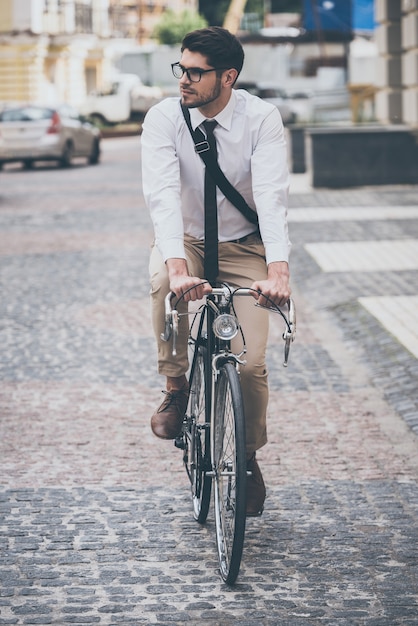 ¡No hay atascos hoy! Hombre joven confiado en gafas mirando a otro lado mientras monta su bicicleta