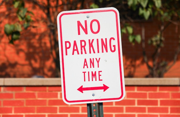 No hay señal de estacionamiento oxidada y envejecida contra un fondo urbano borroso que transmite urbano