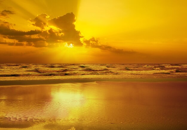 Foto no início da manhã, nascer dourado sobre o mar com um céu nublado, tempo tempestuoso.