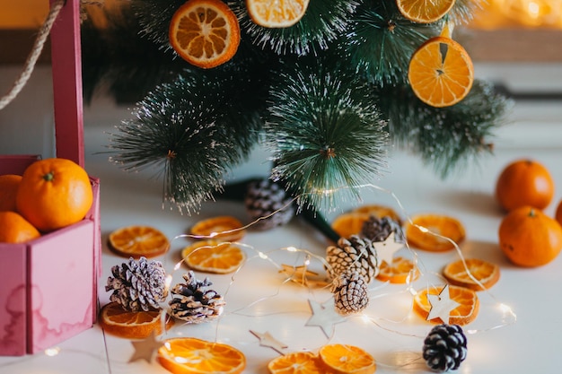No inverno, a árvore é decorada com laranjas secas do lado de fora, galhos verdes contra um fundo desfocado e bokeh amarelo-dourado. decoração festiva em estilo ecológico. feliz natal.