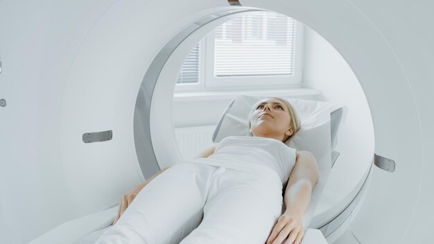 Foto no laboratório médico, o radiologista controla a ressonância magnética ou a ct ou a pet scan com uma paciente feminina submetida a um procedimento de equipamento médico moderno de alta tecnologia