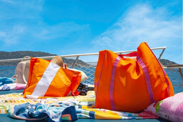 No mar, roupas de férias e bolsas laranjas estão no barco. Saco de férias laranja e branco.